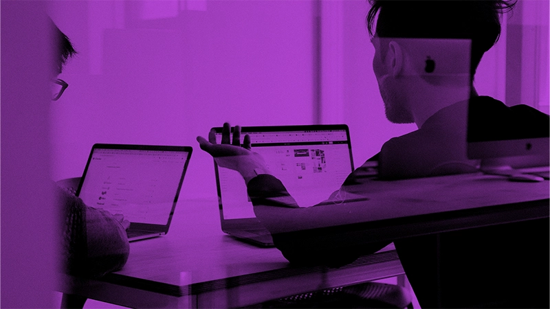 Marketing Automation auf die 1: Effizienter Erfolg dank künstlicher Intelligenz | Online Marketing und Social Media Agentur Zwei Menschen sitzen an ihren Laptops nebeneinander am Tisch