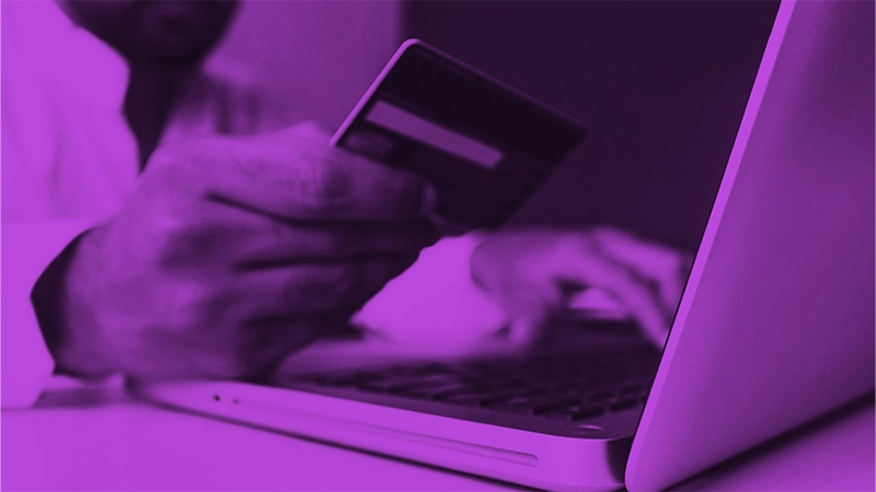 Die Zukunft des Onlinehandels: Wie neue E-Commerce-Formate das digitale Einkaufserlebnis revolutionieren | Online Marketing und Social Media Agentur Ein Mensch sitzt vor einem Laptop und tippt etwas von einer Bankkarte ab